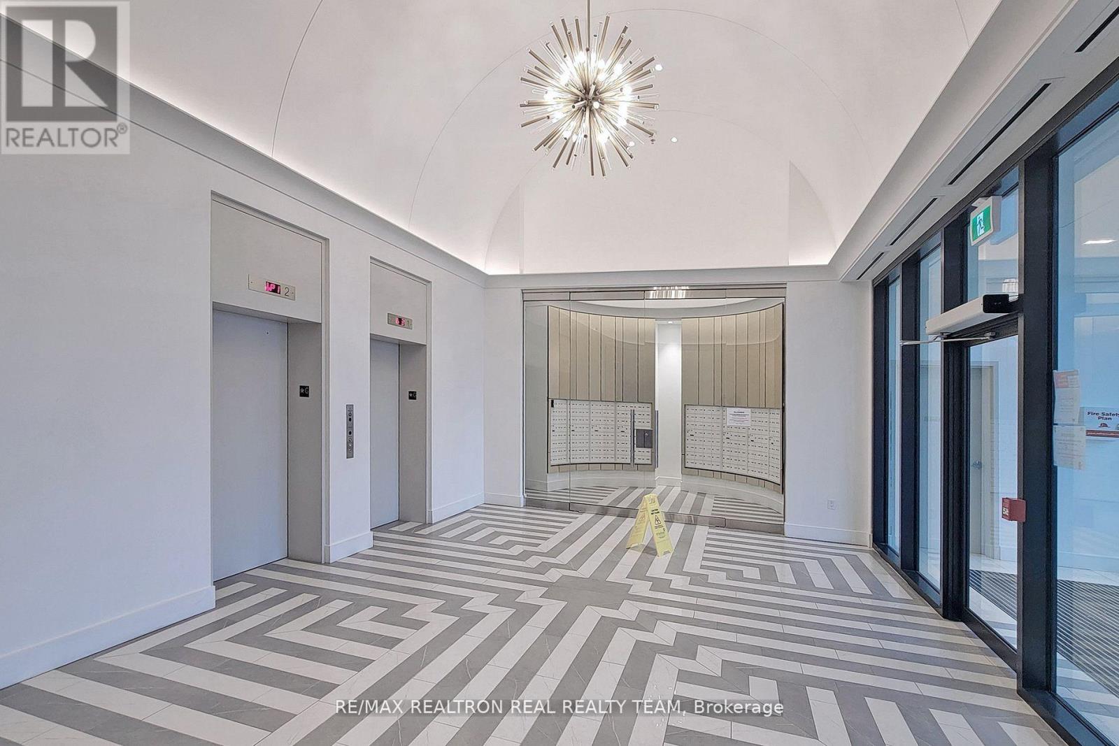 A hallway with a patterned floor and a chandelier hanging from the ceiling.