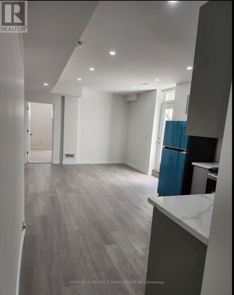 A spacious room with a blue trash bin and grey flooring.