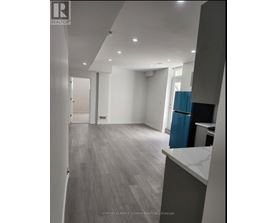 A spacious room with a blue trash bin and grey flooring.