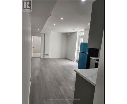A spacious room with a blue trash bin and grey flooring.