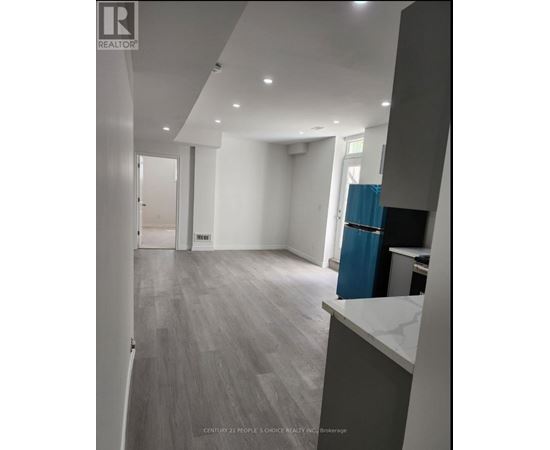 A spacious room with a blue trash bin and grey flooring.