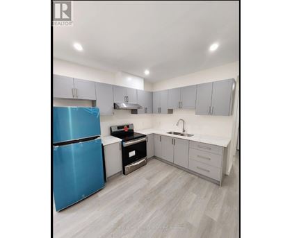 A blue refrigerator is in a kitchen with white cabinets and a sink.
