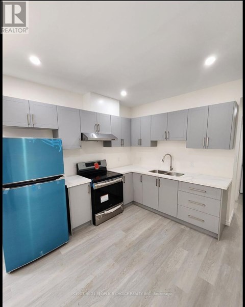 A blue refrigerator is in a kitchen with white cabinets and a sink.