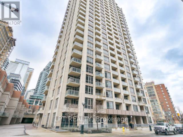 A tall residential building with balconies and a street in front.
