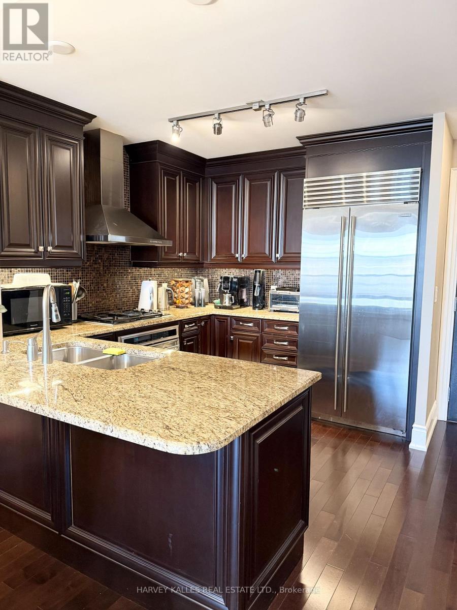 A kitchen with dark wood cabinets and a granite countertop.