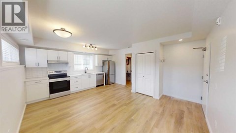 A spacious kitchen with white cabinets and a wooden floor.
