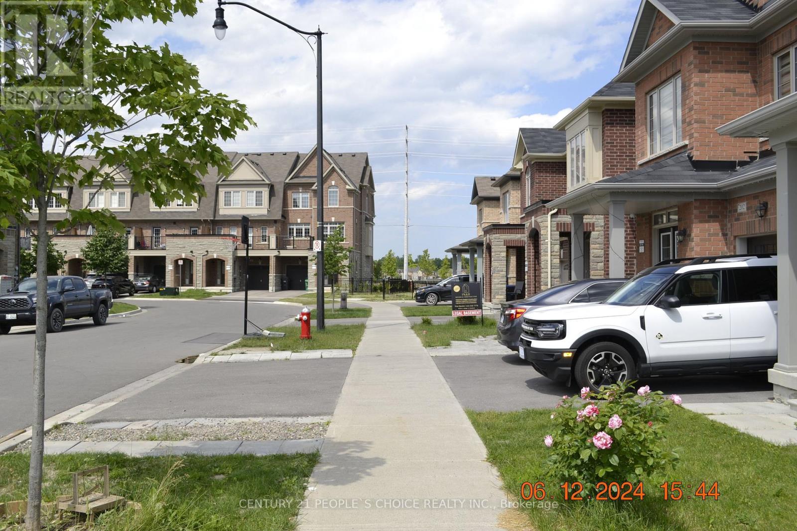 A street view of a residential area with houses on both sides and cars parked along the curb.