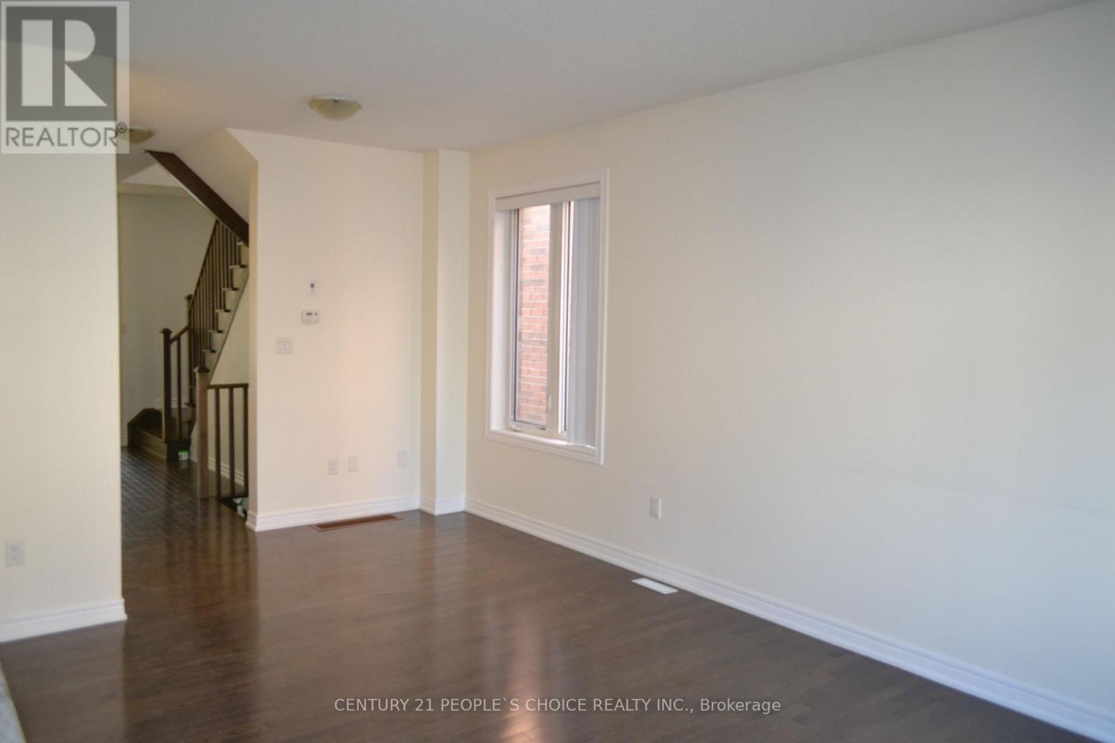 A spacious room with a window and wooden floors.
