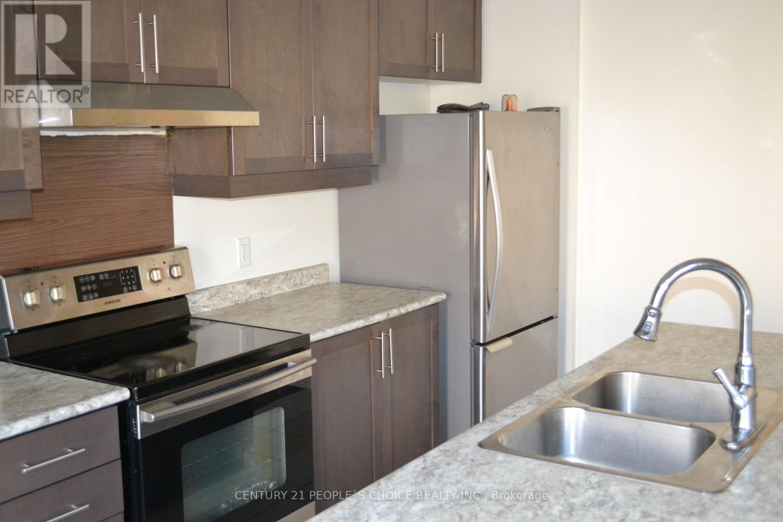 A kitchen with a stove, refrigerator, and sink.