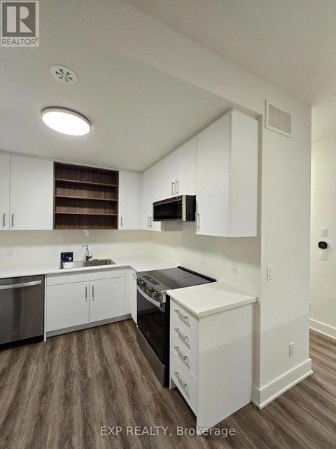 A kitchen with white cabinets and a wooden floor.