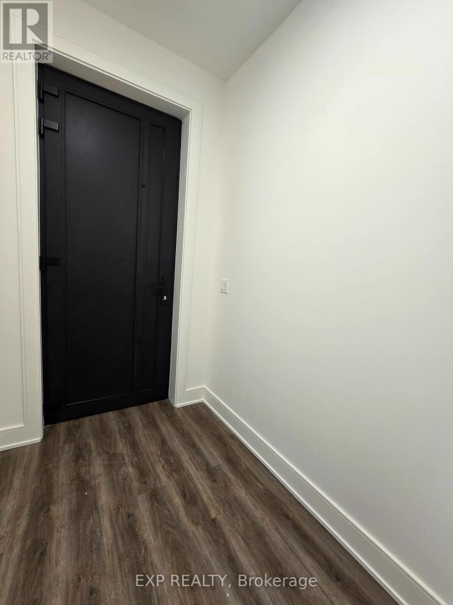 A black door is in a white room with wood flooring.