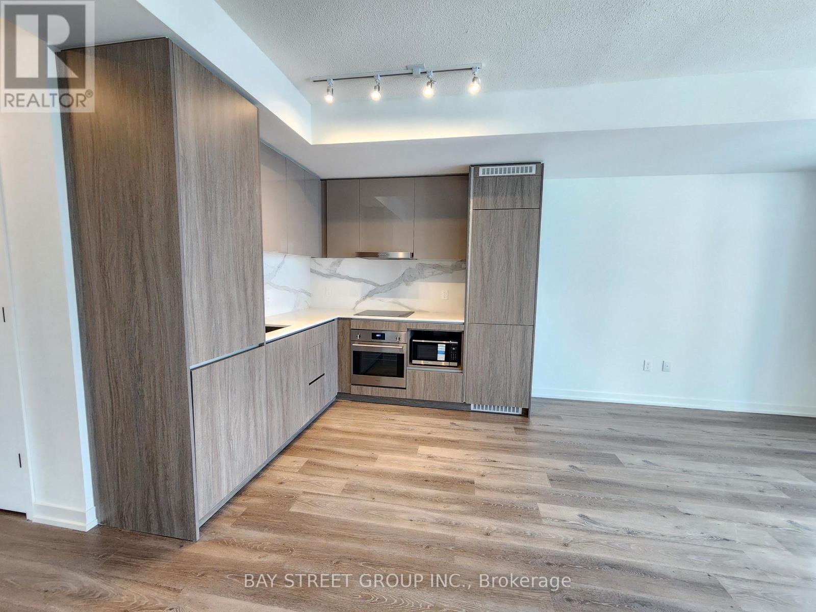A modern kitchen with wooden cabinets and a marble backsplash.