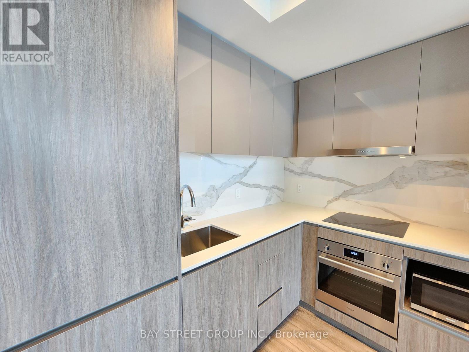 A modern kitchen with a marble countertop and stainless steel appliances.