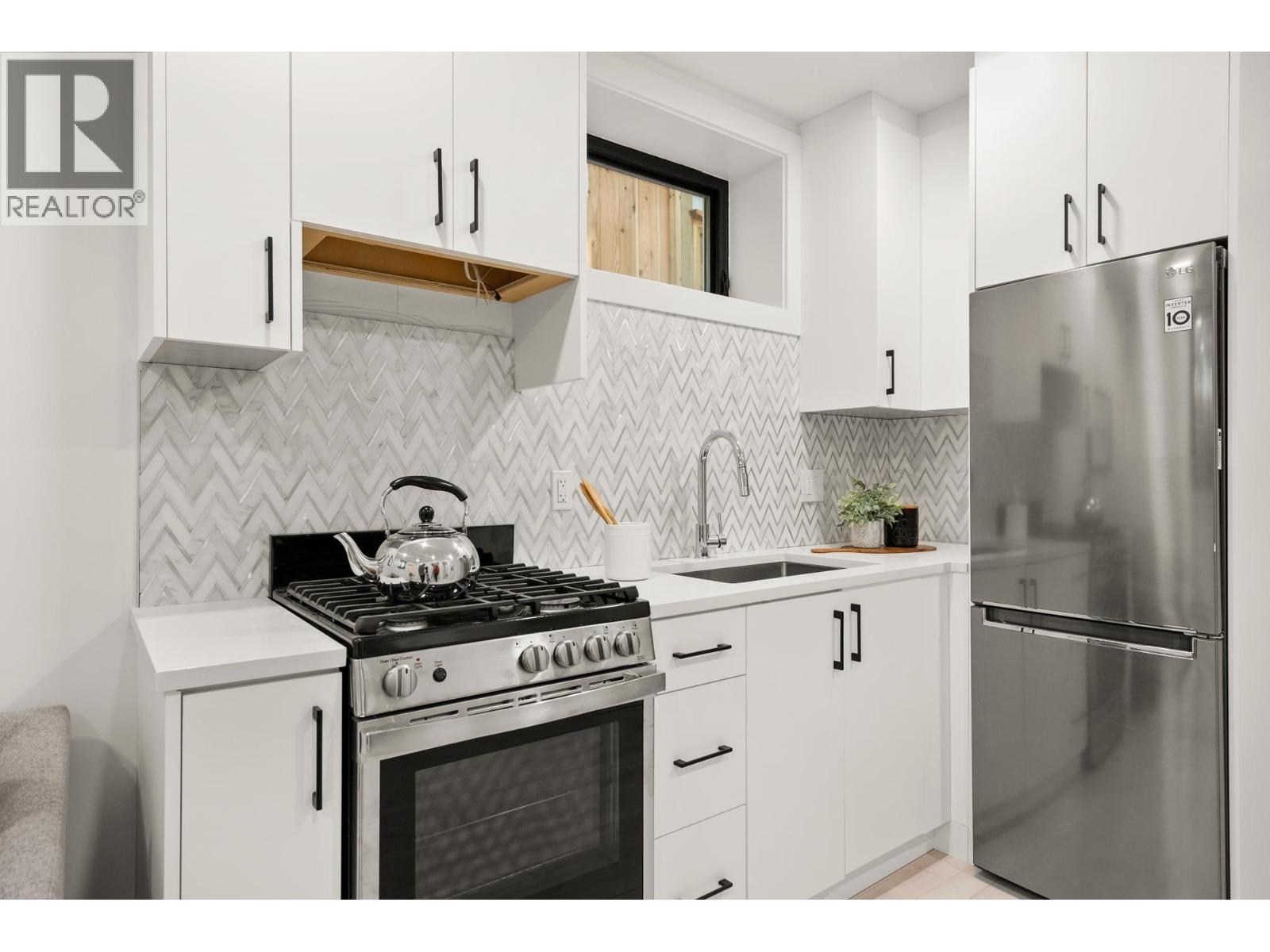 A modern kitchen with white cabinets and a stainless steel refrigerator.