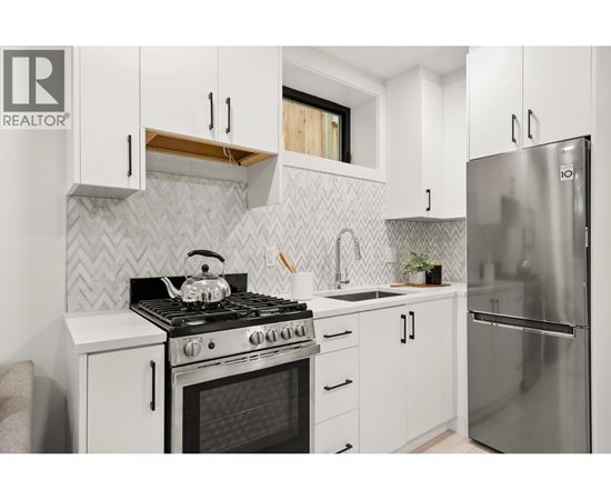 A modern kitchen with white cabinets and a stainless steel refrigerator.