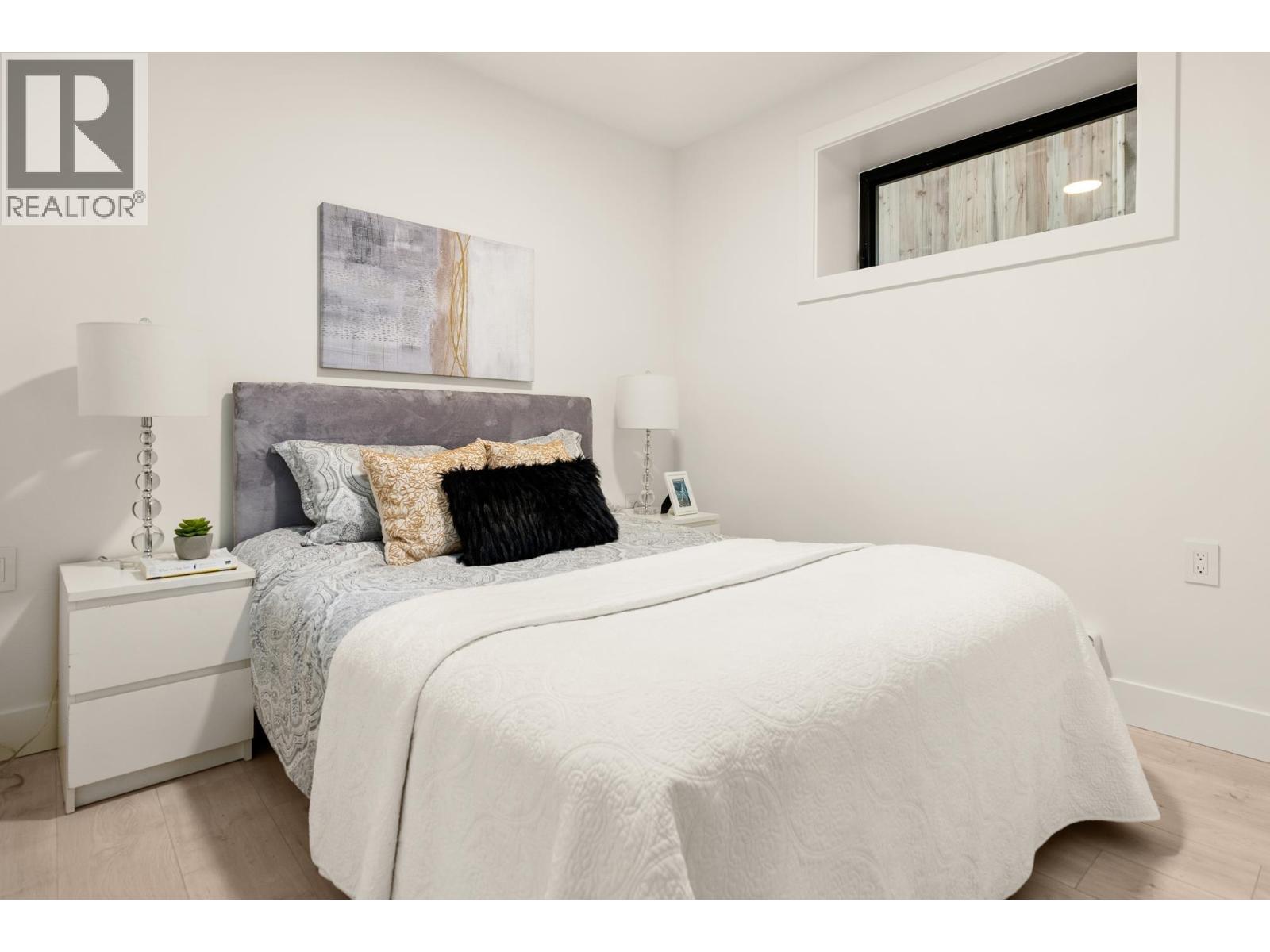 A bedroom with a large bed and a painting on the wall.