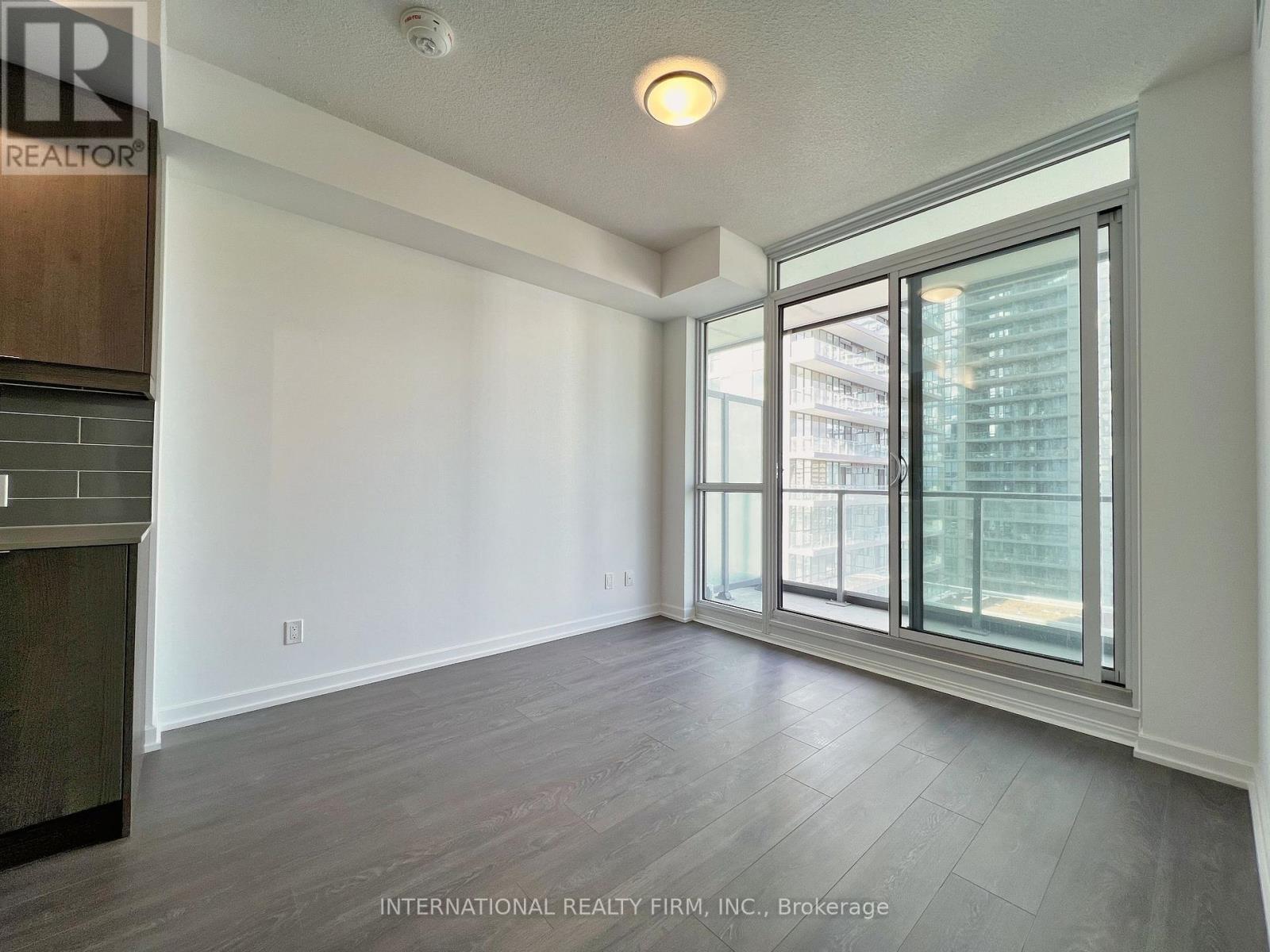 A spacious room with a large window and wooden flooring.