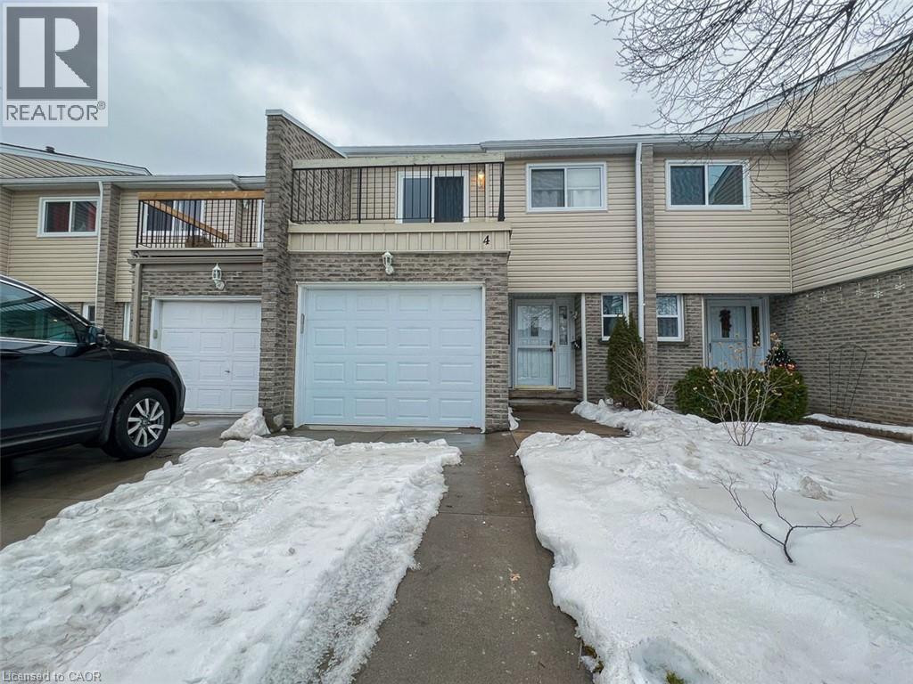 A snow-covered walkway leads to a white garage door in front of a two-story house.