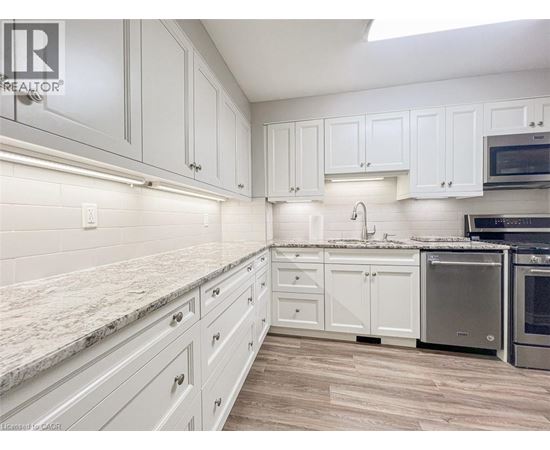 A kitchen with white cabinets and a marble countertop.