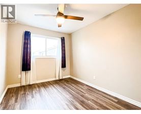 A spacious room with a grey wood floor and white walls.
