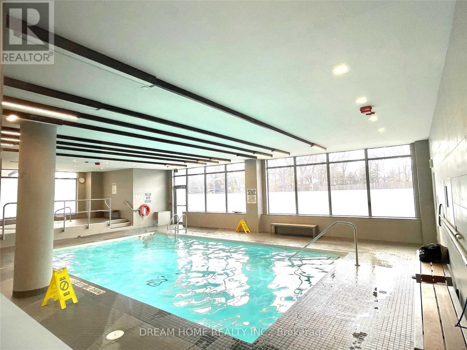 A large indoor swimming pool with a tiled floor and a glass wall.