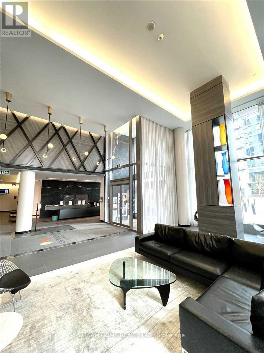 A black leather couch sits in a modern living room with a glass coffee table.
