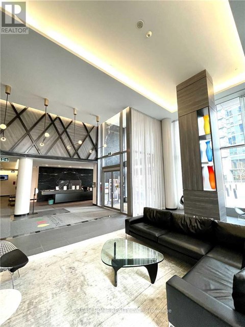 A black leather couch sits in a modern living room with a glass coffee table.