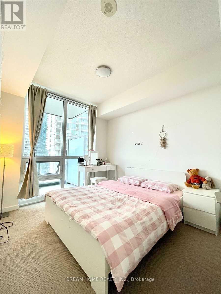 A bedroom with a bed, nightstand, and window.