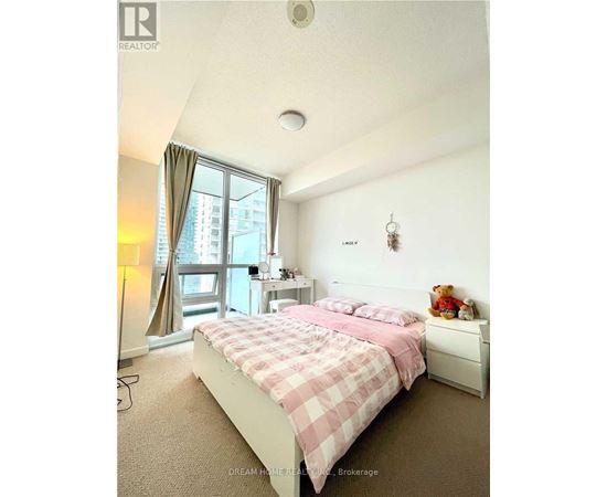 A bedroom with a bed, nightstand, and window.
