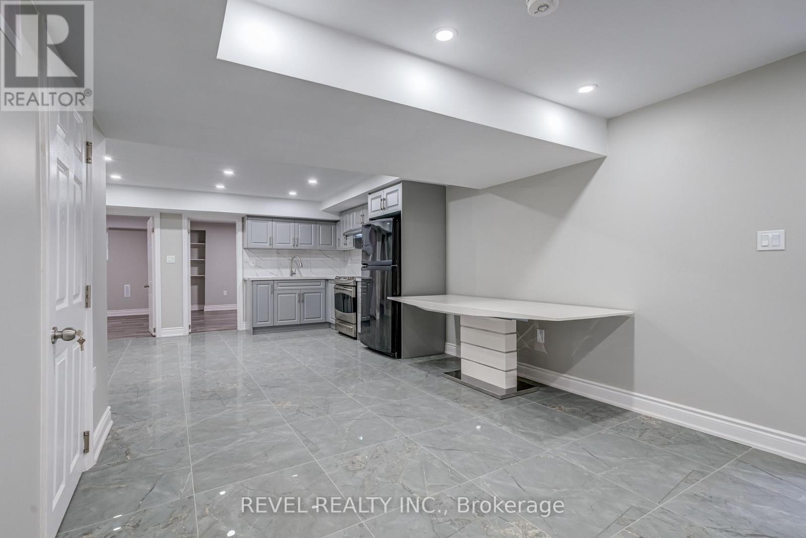 A spacious kitchen area with a refrigerator, sink, and cabinets.