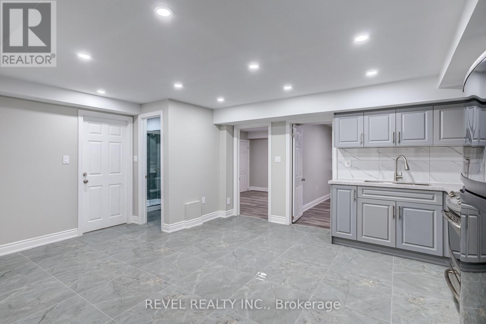 A spacious kitchen and living room with a marble floor and white walls.