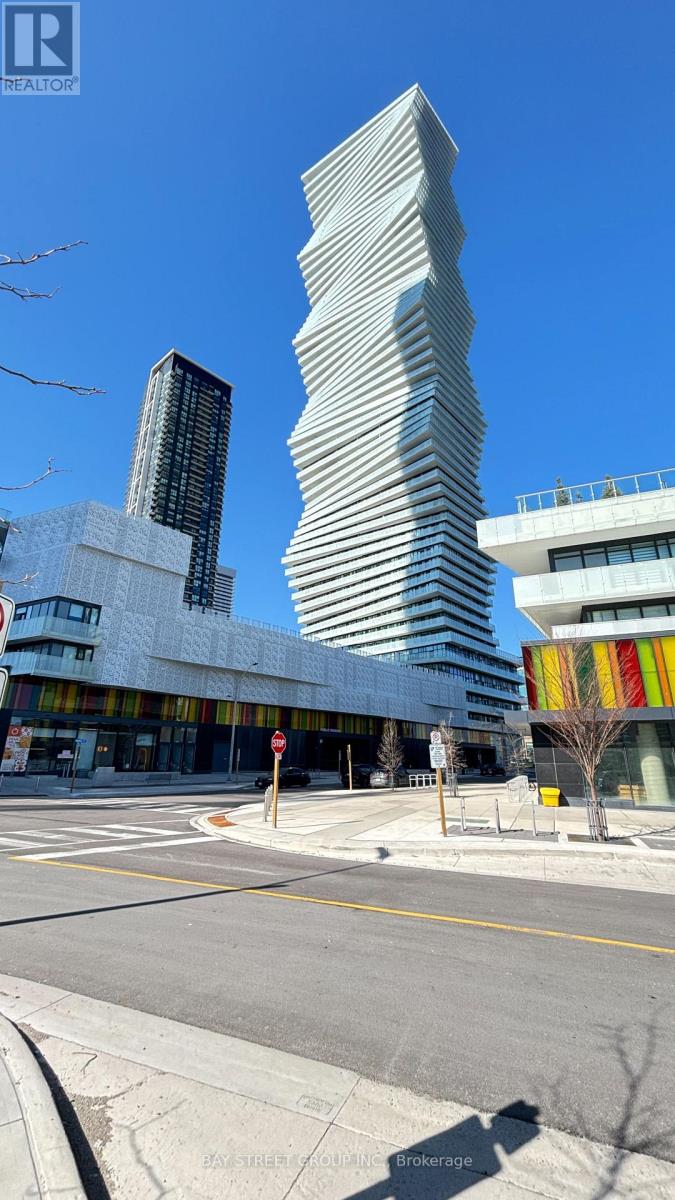 A tall, white building with a curved design stands in front of a smaller building.