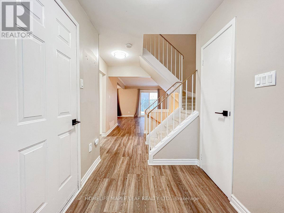 A hallway with a wooden floor and white walls leading to a staircase.