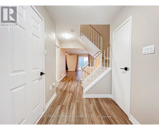 A hallway with a wooden floor and white walls leading to a staircase.