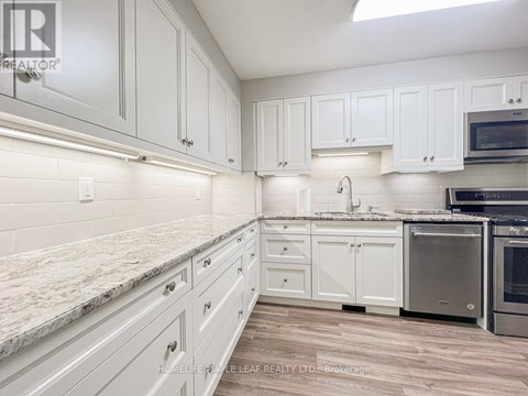 A kitchen with white cabinets and a marble countertop.