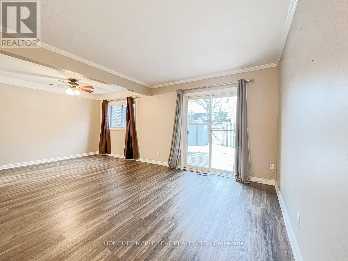 A spacious room with wooden flooring and a sliding glass door leading to a balcony.