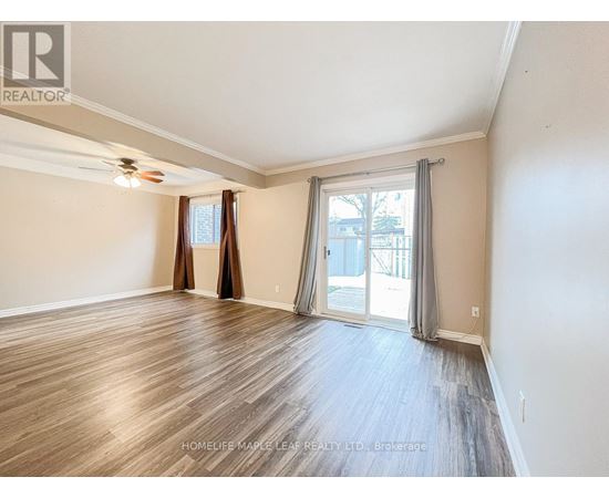 A spacious room with wooden flooring and a sliding glass door leading to a balcony.
