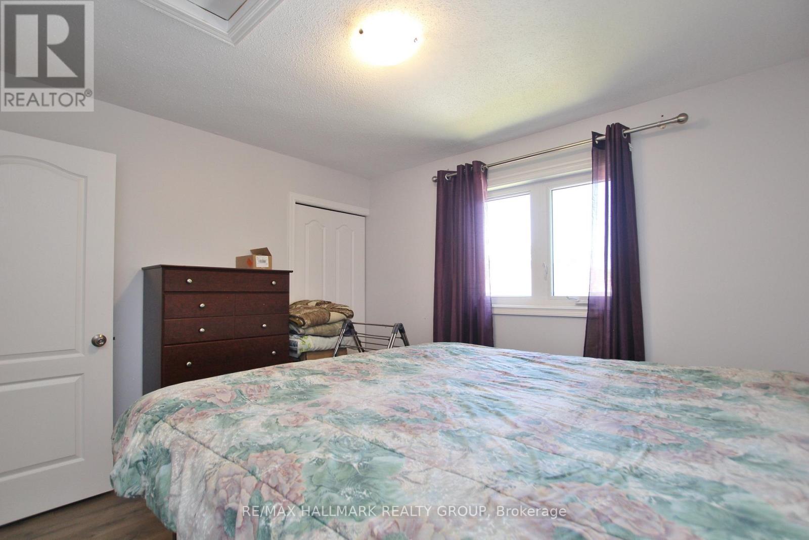 A bedroom with a large bed and a window with curtains.