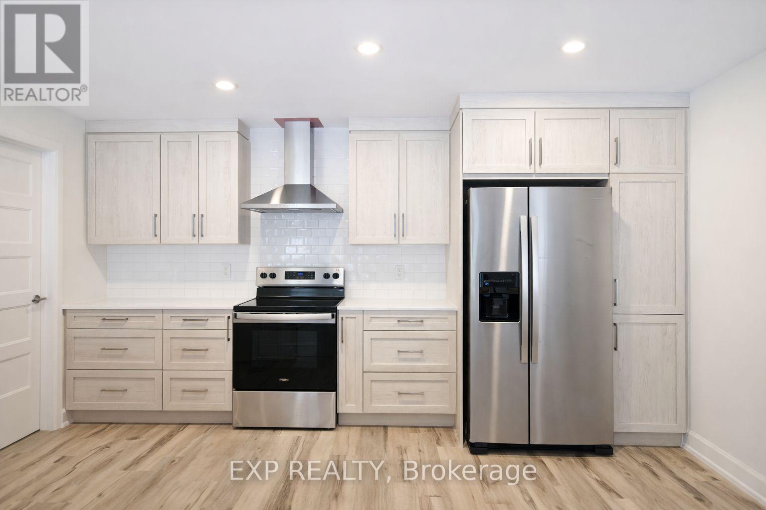 A kitchen with white cabinets and a stainless steel refrigerator.
