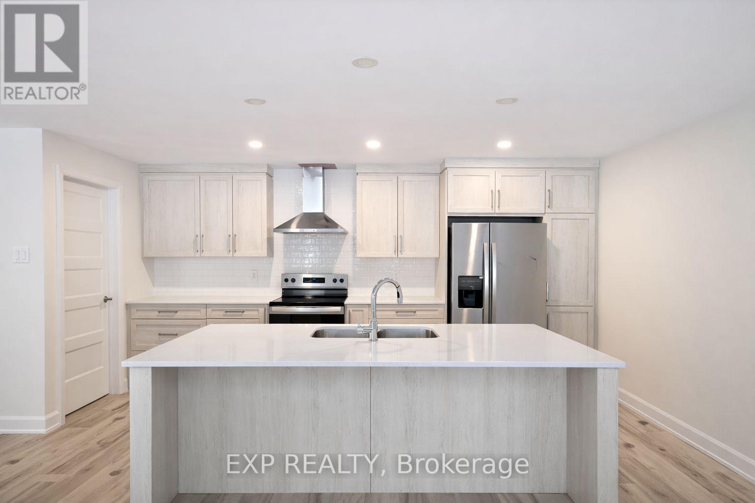 A kitchen with white cabinets and a white island with EXP Realty Brokerage in the middle.