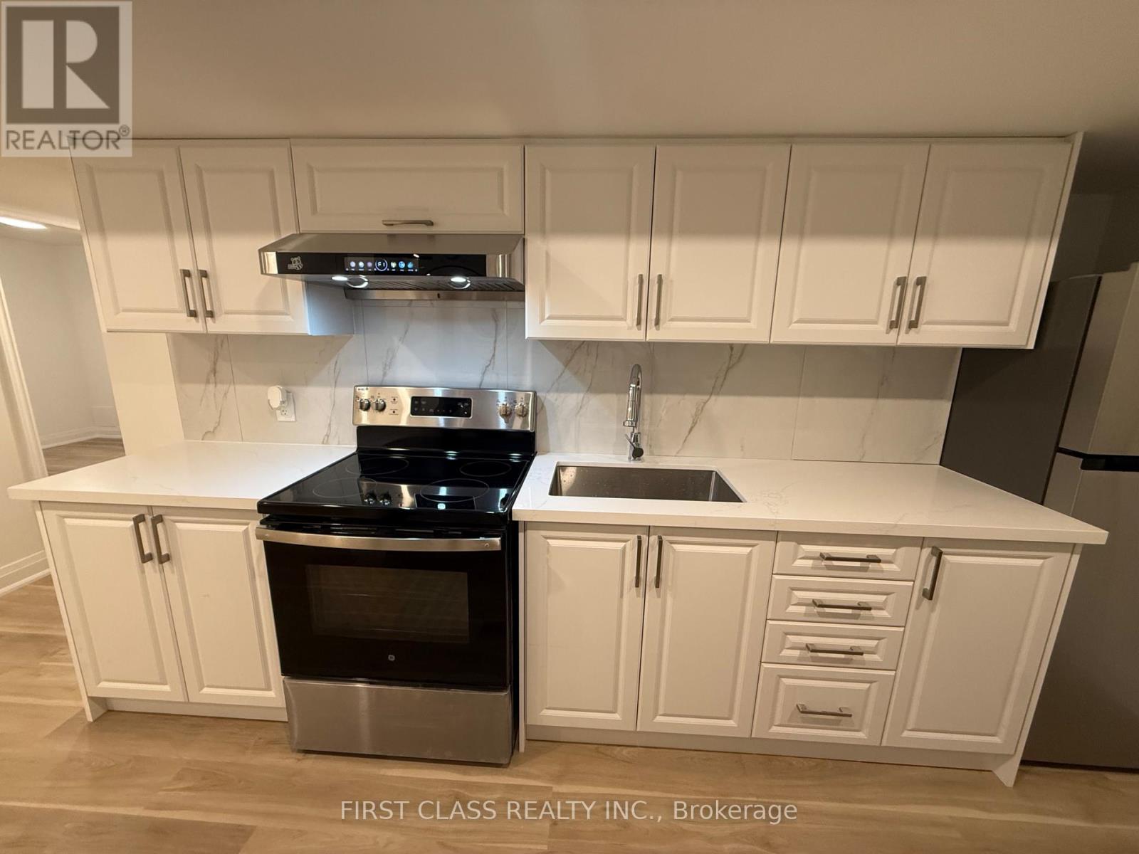A kitchen with white cabinets and a black stove top.
