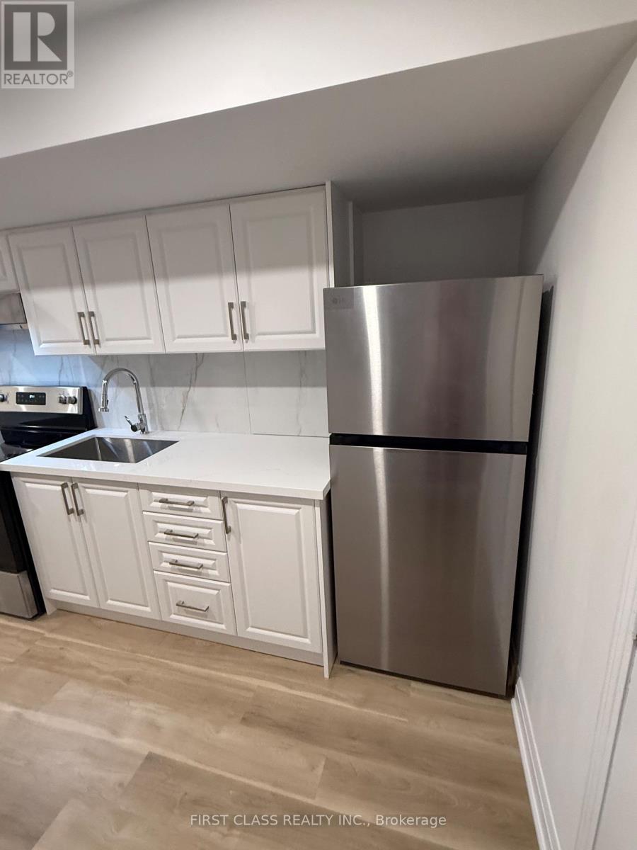 A kitchen with white cabinets and a stainless steel refrigerator.