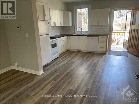A kitchen with white cabinets and a wooden floor.