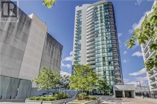 A tall building with many windows is surrounded by trees and other buildings.