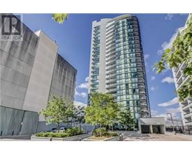 A tall building with many windows is surrounded by trees and other buildings.