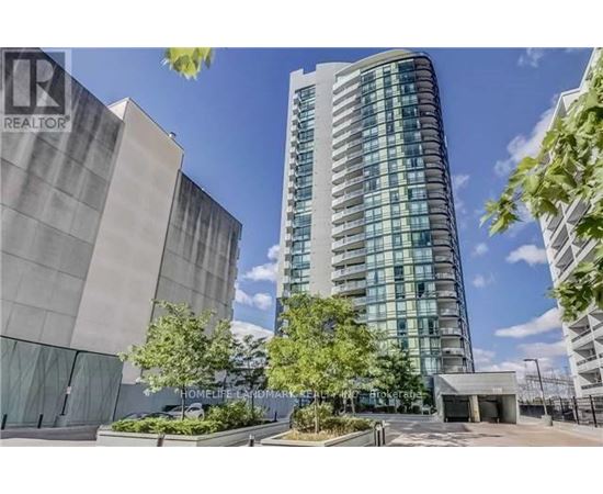 A tall building with many windows is surrounded by trees and other buildings.