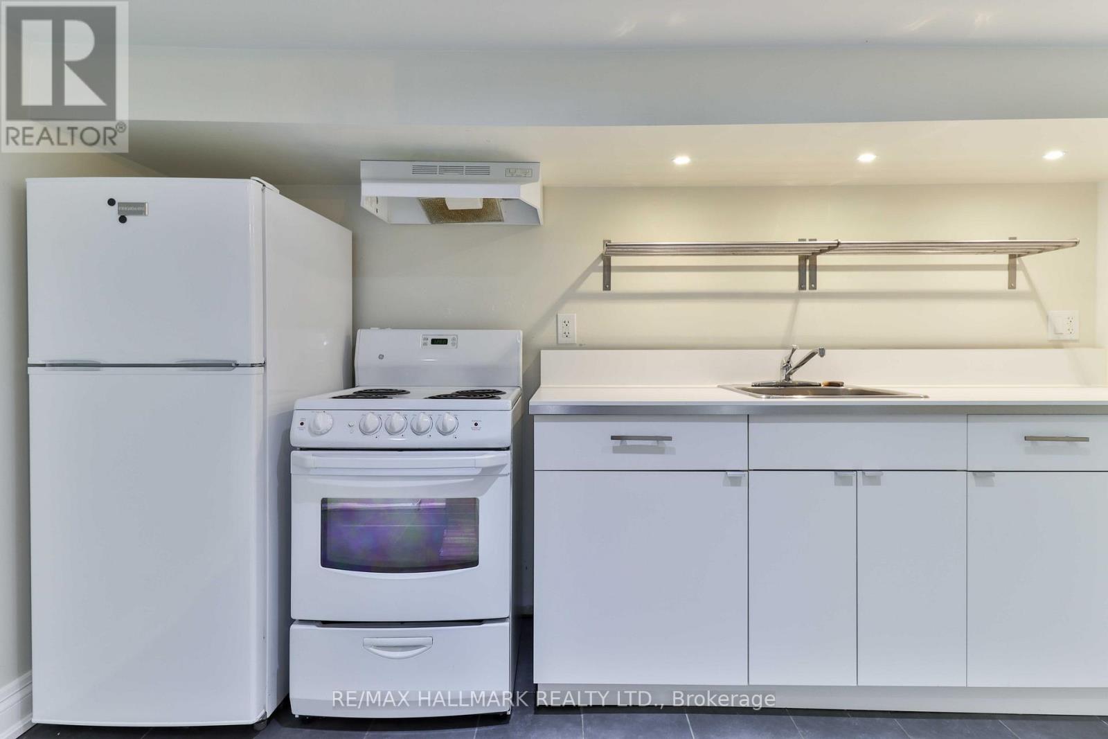 A white kitchen with a refrigerator, oven, and stove.