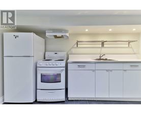 A white kitchen with a refrigerator, oven, and stove.