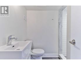 A white bathroom with a toilet, sink, and marble tiles.