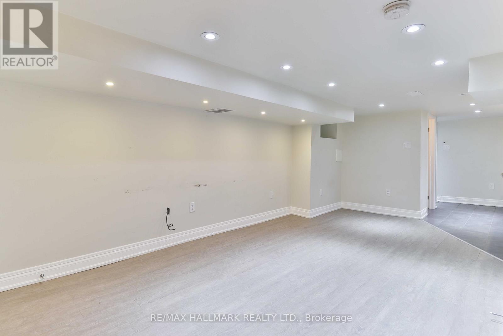 A spacious room with a light-colored floor and walls, and a door on the right side.